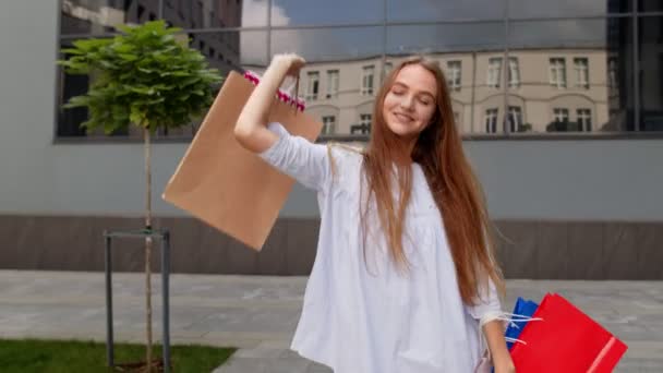 Alışveriş merkezinden alışveriş torbalarıyla yürüyen güzel bir kız, Kara Cuma günü satın almaktan memnun. — Stok video