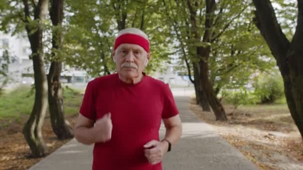 Anciano deporte corredor hombre de entrenamiento. Entrenamiento cardio afuera en el parque por la mañana. Personas mayores activas — Vídeos de Stock