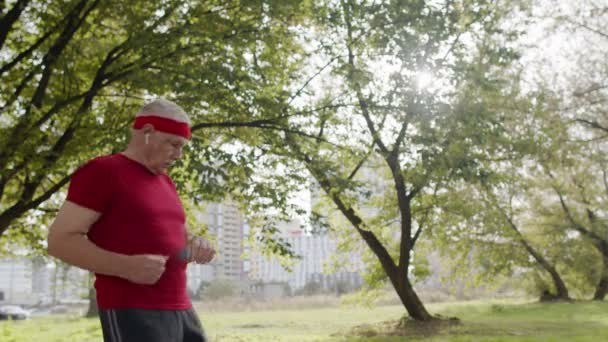 Hombre corredor deportivo senior que usa la pantalla táctil de toque de reloj inteligente, resultado de seguimiento después del entrenamiento de fitness — Vídeos de Stock