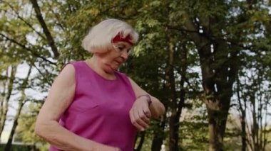 Kıdemli sporcu kadın akıllı saat, dokunmatik ekran, takip sonucu kullanıyor. Fitness egzersizi