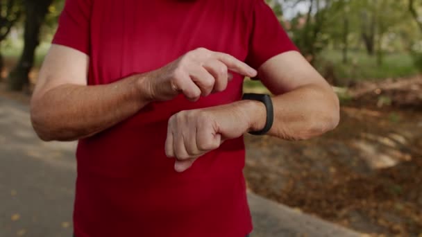 Vieil homme coureur senior qui commence à taper sur l'écran tactile de la montre intelligente, la distance de suivi, la vérification du pouls — Video