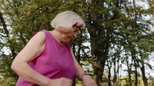 Senior sport runner vrouw met behulp van slimme horloge, tikken touchscreen, tracking resultaat. Fitnesstraining — Stockvideo