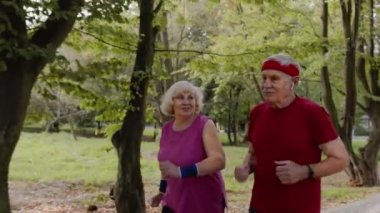 Sportif, olgun bir aile çifti birlikte koşuyor. Kıdemli karı koca kardiyo egzersizleri yapıyor.