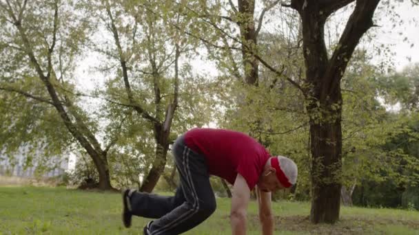 Uomo anziano sportivo che fa esercizi push up. Allenamento cardio fuori nel parco della città al mattino — Video Stock