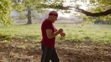 Park yolunda koşan son sınıf öğrencisi bir erkek. Olgun koşucu adam eğitimi, müzik dinlemesi