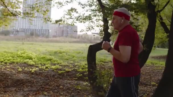 Vista laterale di anziano corridore sportivo uomo formazione. Allenamento cardio fuori nel parco della città al mattino — Video Stock