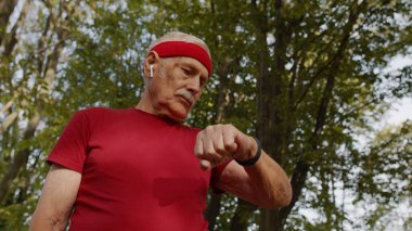 Parktaki kıdemli koşucu akıllı saat, takip mesafesi, nabız kontrolü spor sonrası nabız kontrolü yapıyor.