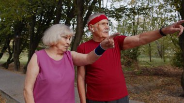 Sportif aile koşmak için rota çiziyor. Kıdemli erkek ve kadın fitness maratonuna hazırlanıyor.