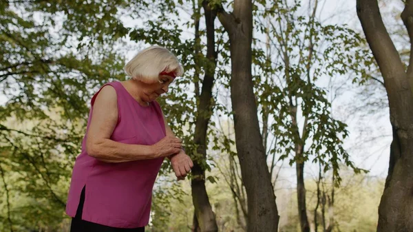 Femme coureuse de sport senior utilisant la montre intelligente tapant sur l'écran tactile, le résultat de suivi. Entraînement de fitness — Photo