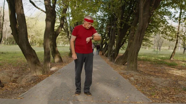 Senior homem corredor esporte usando relógio inteligente tocando touchscreen, rastreamento resultado após o treino de fitness — Fotografia de Stock