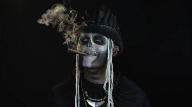 Korkunç Cadılar Bayramı iskelet makyajlı uğursuz adam başını kaldırıp puro içiyor.