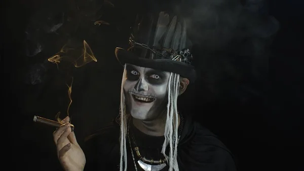 Страшний чоловік у скелеті Хеллоуїн косплей костюм куріння сигари, усміхнений, сміється — стокове фото