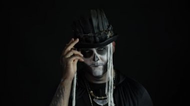 Korkunç cadılar bayramı makyajlı bir adam yüzünü buruşturuyor, korkunç bir şekilde gülümsüyor. Voodoo ayinleri. Baron Cumartesi.