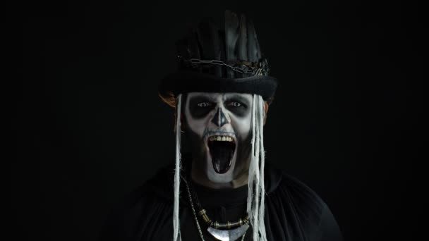 Hombre aterrador en disfraz de cosplay de Halloween esqueleto. Chico en espeluznante cráneo maquillaje haciendo caras — Vídeo de stock