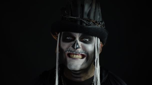 Чоловік з скелетним макіяжем намагається налякати, відкриваючи рот і показуючи брудні чорні зуби і язик — стокове відео