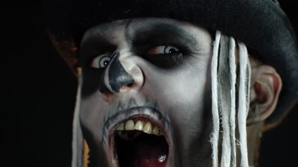 Закрыть кадры зловещего человека с макияжем скелета Хэллоуина, делающего лица, пытаясь напугать — стоковое видео