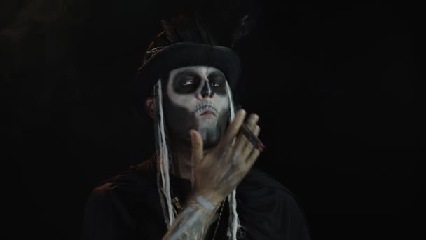 Gruseliger Mann mit Skelett-Make-up im Zylinder. Kerl raucht Zigarre, macht Gesichter, schaut in die Kamera — Stockvideo