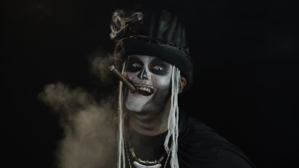 Homem assustador no esqueleto Halloween cosplay traje fumar charuto, sorrindo, rindo. Movimento lento — Vídeo de Stock