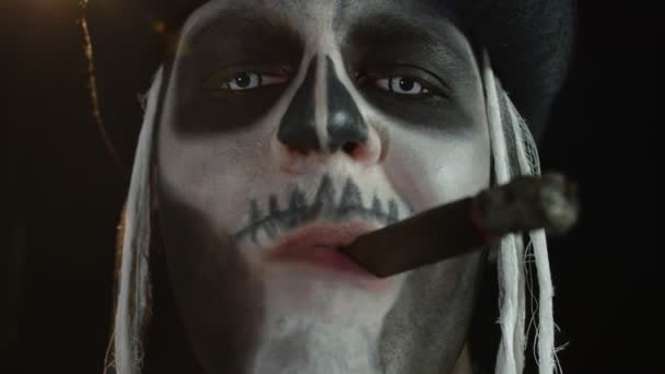 Close up shot of creepy man face with skeleton makeup smoking cigar, making faces, looking at camera — Stock Video