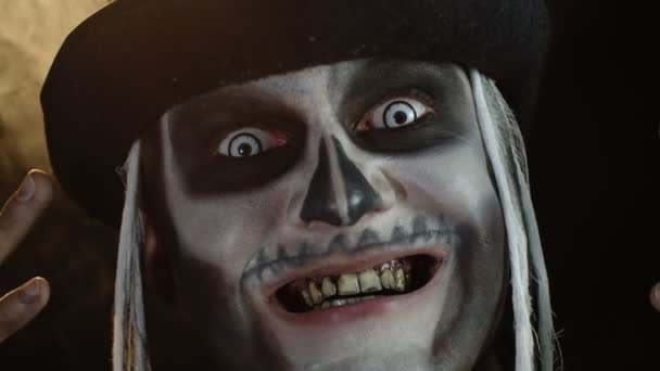 Человек в костюме косплея на Хэллоуин. Парень в жутком макияже черепа смотрит широко открытыми глазами — стоковое видео
