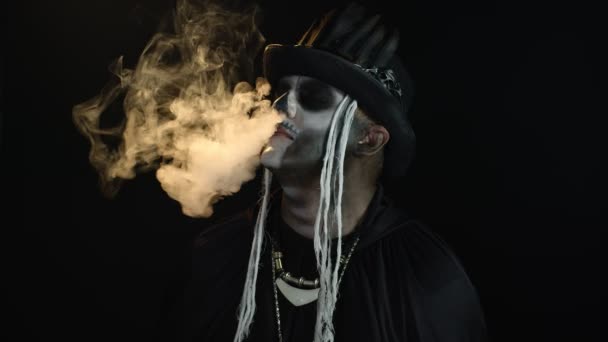 Finsterer Mann mit professionellem Totenkopf-Make-up atmet Zigarettenrauch aus Mund und Nase — Stockvideo