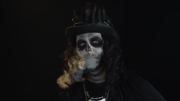 Przerażający facet z makijażem szkieletowym. Facet wydychający papierosa paląc z ust i uśmiechając się — Wideo stockowe