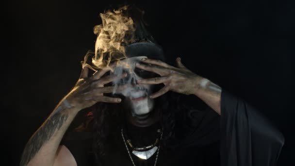 Чоловік у скелеті Хеллоуїн моторошний макіяж черепа видихає сигарету дим з рота, посміхаючись — стокове відео