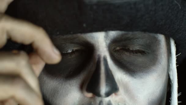 Close-up van enge man gezicht in carnaval schedel Halloween make-up van skelet ziet er griezelig op camera — Stockvideo