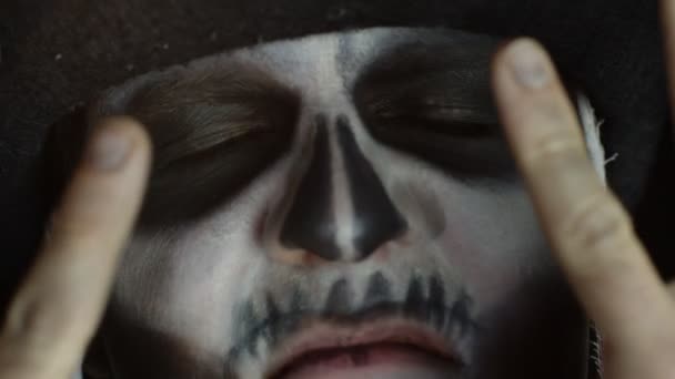 Close-up man face in skeleton Halloween cosplay removing hands from face and looking wide open eyes — Stock Video