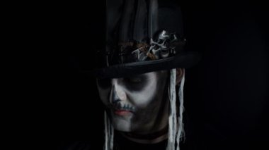 İskelet giymiş korkunç bir adam. Karanlıktan görünen Cadılar Bayramı kostümü.