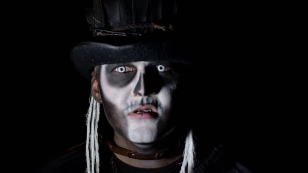 Синістер з макіяжем скелета з'являється з темряви, коли на нього падає світло, створюючи обличчя — стокове відео