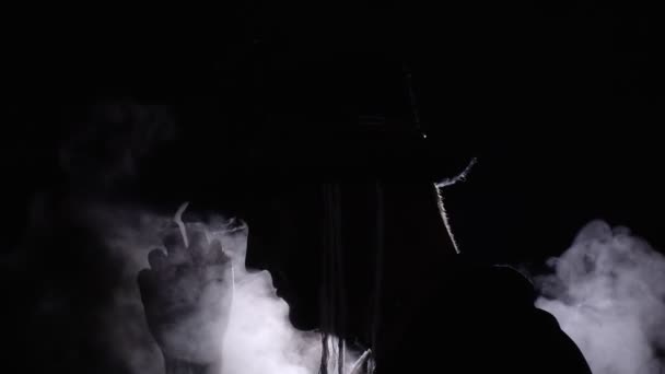 Gruseliger Mann mit Skelett-Make-up erscheint aus der Dunkelheit, wenn Licht auf ihn fällt und macht Gesichter — Stockvideo