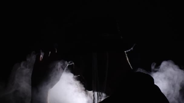 Gruseliger Mann im Skelett-Halloween-Kostüm erscheint aus der Dunkelheit, als Licht auf ihn fällt