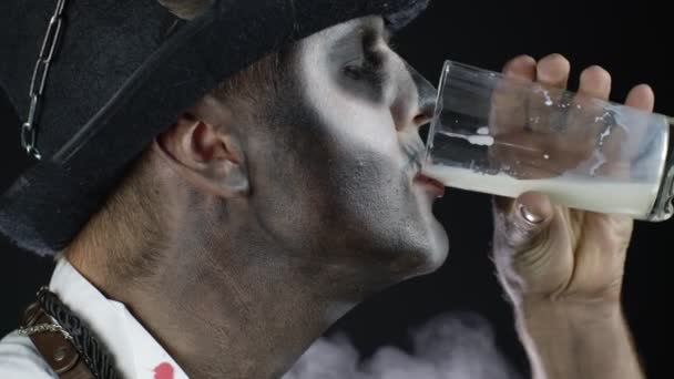 Effrayant gars en costume de carnaval de squelette Halloween regardant caméra, boit du lait à partir d'un verre — Video