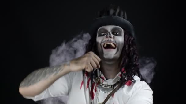 Przerażający facet z szkieletowym makijażem na Halloween w zakrwawionej koszuli. Facet słuchający muzyki, tańczący, świętujący — Wideo stockowe