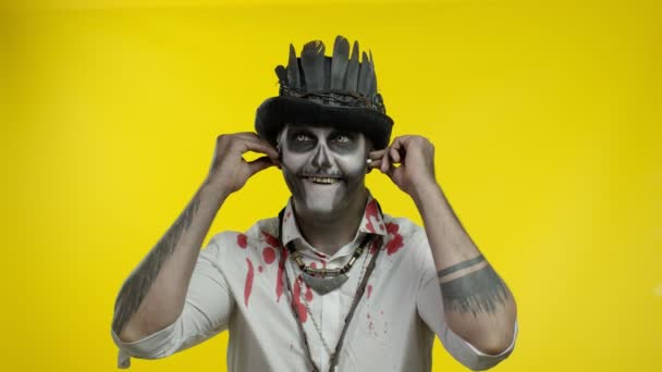 Finsterer Mann mit schrecklichem Halloween-Skelett-Make-up setzt Kopfhörer auf, beginnt zu tanzen, zu feiern — Stockvideo