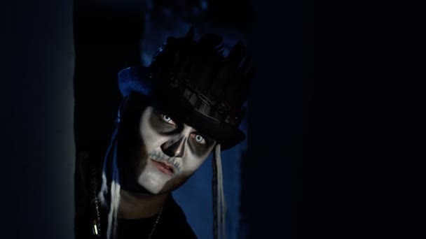 Przerażający człowiek z halloweenowym makijażem szkieletowym powoli pojawia się z ciemnego kąta, próbując przestraszyć — Wideo stockowe