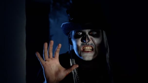 Děsivý muž s halloweenskou kostrou make-up se rychle objeví z tmavého rohu, snaží se vystrašit — Stock video