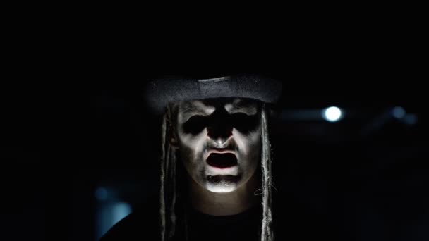 Homem assustador com maquiagem esqueleto aparecendo da escuridão quando a luz cai sobre ele, fazendo rostos — Vídeo de Stock