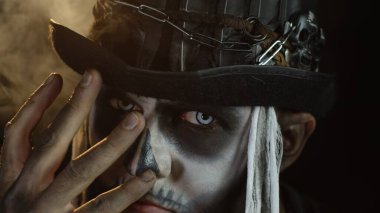 İskelet cadılar bayramı kostümlü adam. Korkunç kafatası makyajlı adam kameraya bakıyor.