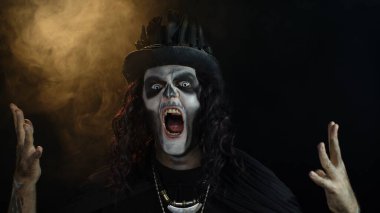 İskelet makyajlı ürkütücü bir adam. Adam başını çeviriyor ve kameraya bakıyor, korkutmaya çalışıyor.