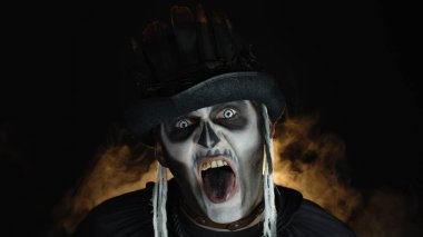 İskelet makyajlı ürkütücü, deli bir adam. Kızgın suratlar yapan, başını sallayan, dilini gösteren bir adam.