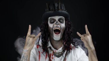 Cadılar Bayramı kostümlü, kanlı tişörtlü, müzik dinleyen, dans eden, kutlama yapan korkunç bir adam.