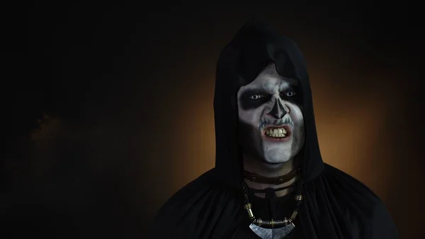 Finsterer Mann mit Halloween-Skelett-Make-up macht Gesichter, blickt in die Kamera und versucht Angst zu verbreiten — Stockfoto