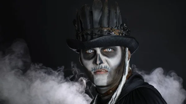 Зловещий человек с макияжем на Хэллоуин поворачивает голову и смотрит в камеру, пытаясь напугать — стоковое фото
