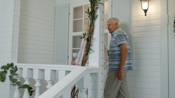 Pareja de ancianos mayores tomando café, mirando hacia el porche en casa. Familia madura en casa propia — Vídeo de stock