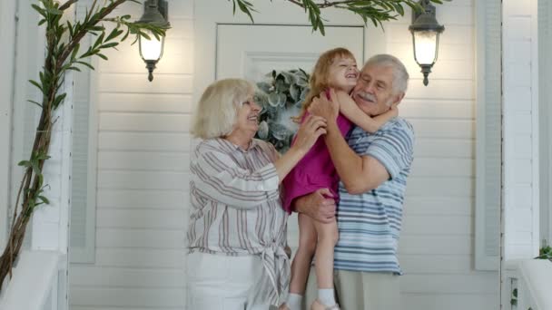 Feliz abuelo mayor y abuela pareja sosteniendo nieta en las manos en el porche en casa — Vídeos de Stock