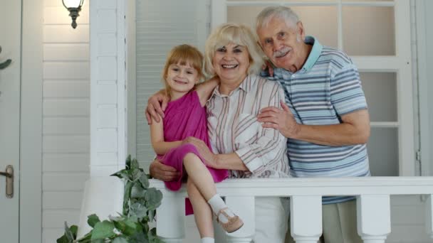 Senior grandfather and grandmother couple with granddaughter waving hand, smiling, saying hello — Stock Video