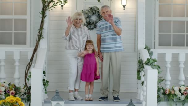 祖父と祖母のカップルの孫娘手を振って、笑顔、こんにちはと言っ — ストック動画
