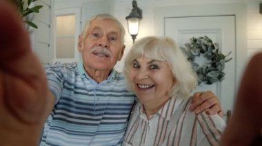 Üst düzey Kafkasyalı çift video görüşmesi için cep telefonu kullanıyor, verandada selfie çekiyor.